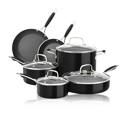 A sleek, black cookware set of eight pieces, including pots and pans with glass lids and silver handles, arranged neatly on a reflective surface.