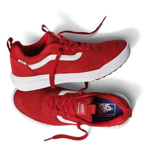 A pair of bright red sneakers with white soles and accents. One sneaker lies on its side, revealing the brand logo on the insole. The laces are loosely tied.