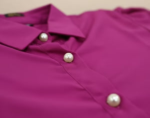 Close-up of a purple shirt with pearl buttons on a beige background