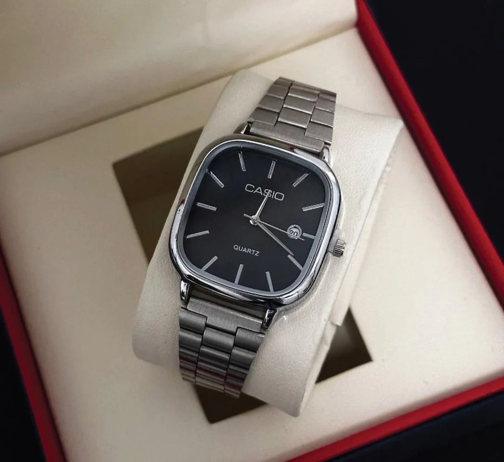 Casio watch with black face and silver metal strap on a white cushion inside a red and beige box.