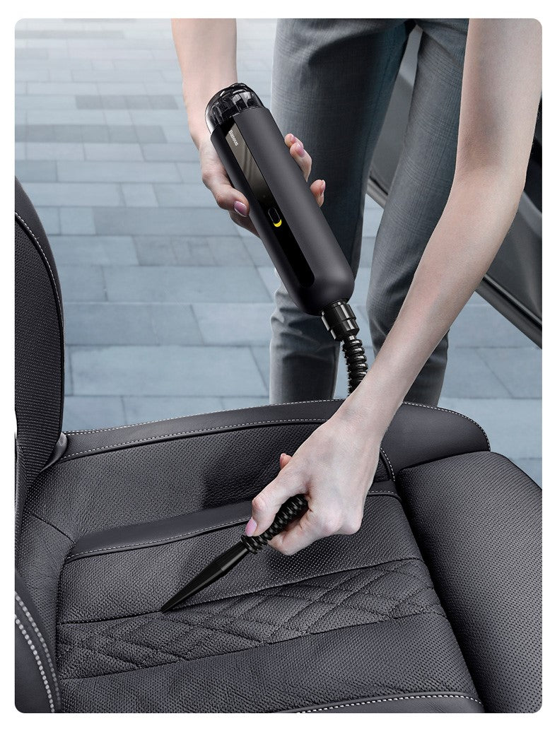 Person cleaning a car seat with a handheld vacuum cleaner.