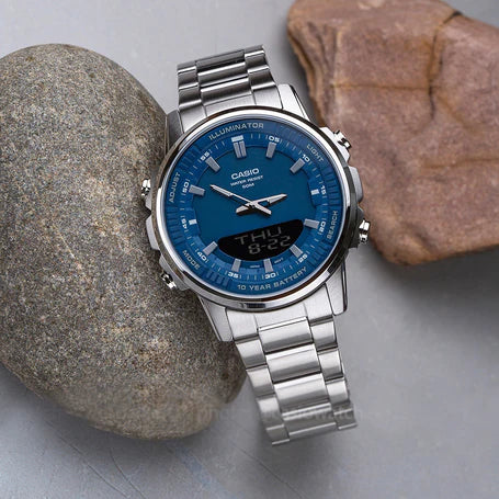 Silver Casio watch with blue face on a stone surface