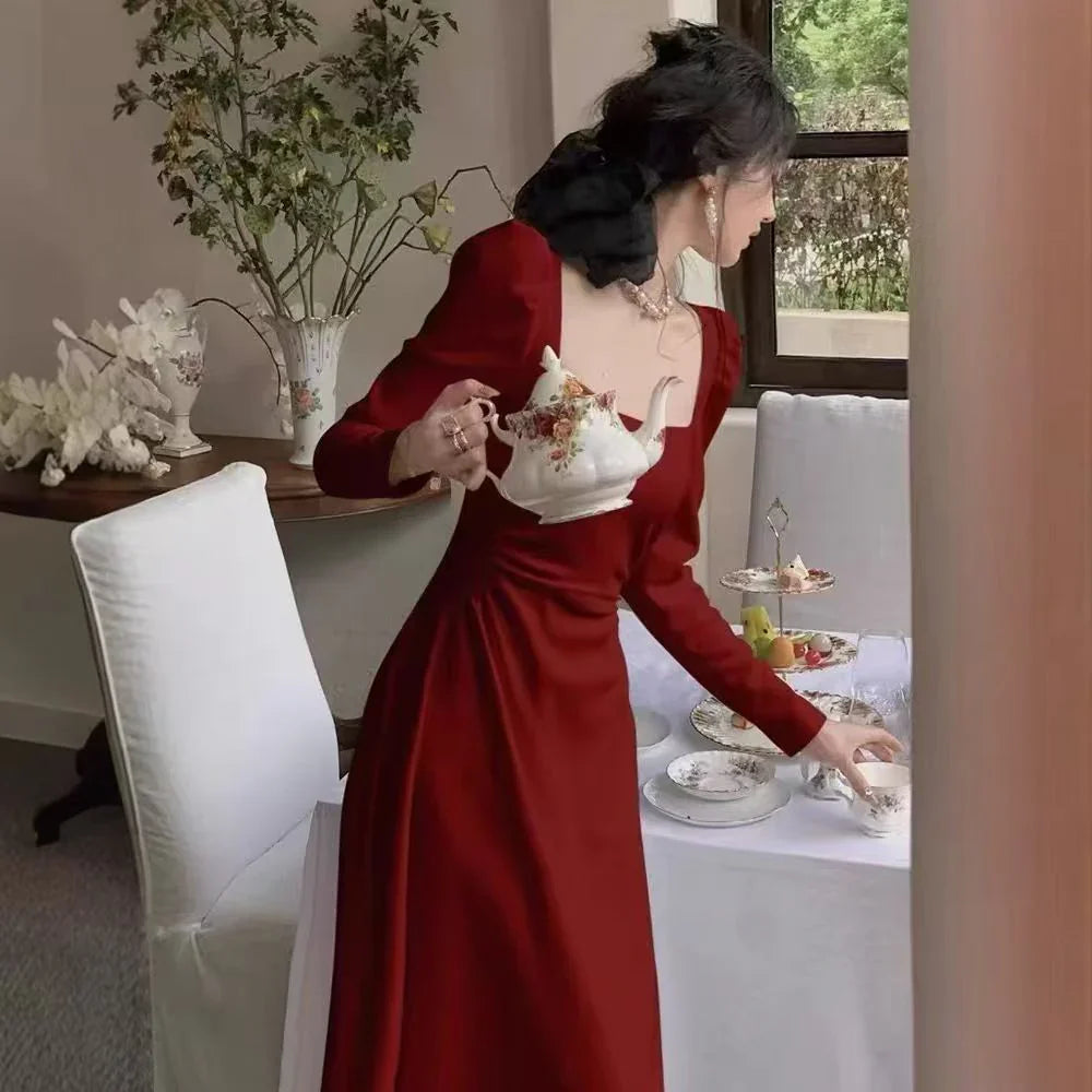 Woman in a red dress serving tea at a table with a decorative setting.