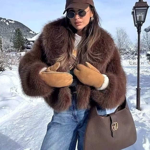 Person wearing a brown fur coat and gloves in a snowy landscape