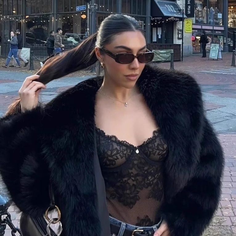 Woman wearing a black fur coat and lace top on a city street.