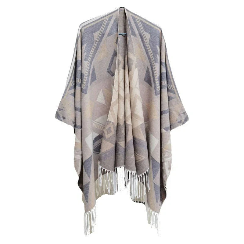 Geometric patterned poncho with fringe details on a white background