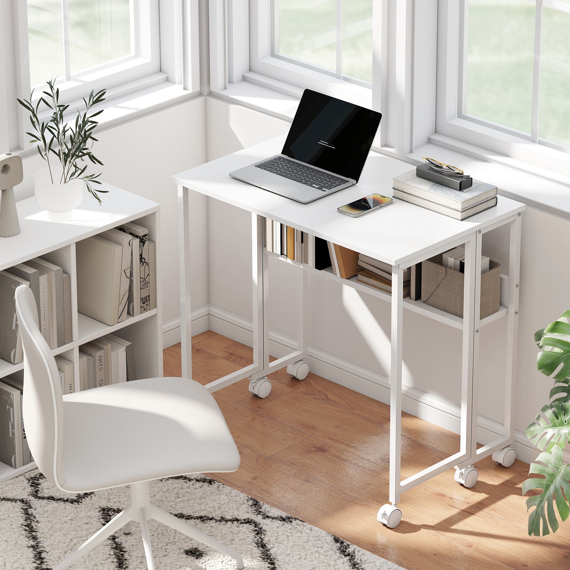 White office desk with laptop, chair, and books in a bright room.