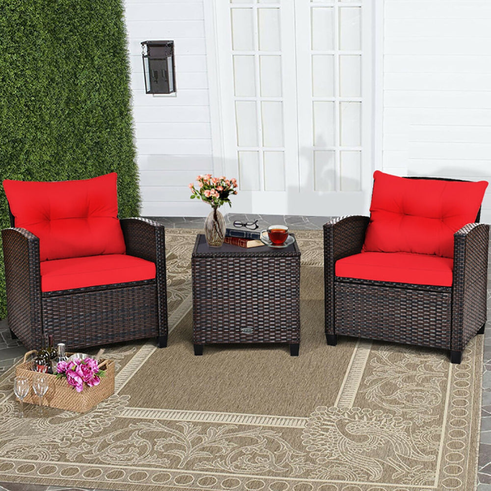 Outdoor patio set with red cushions on chairs and a small table.