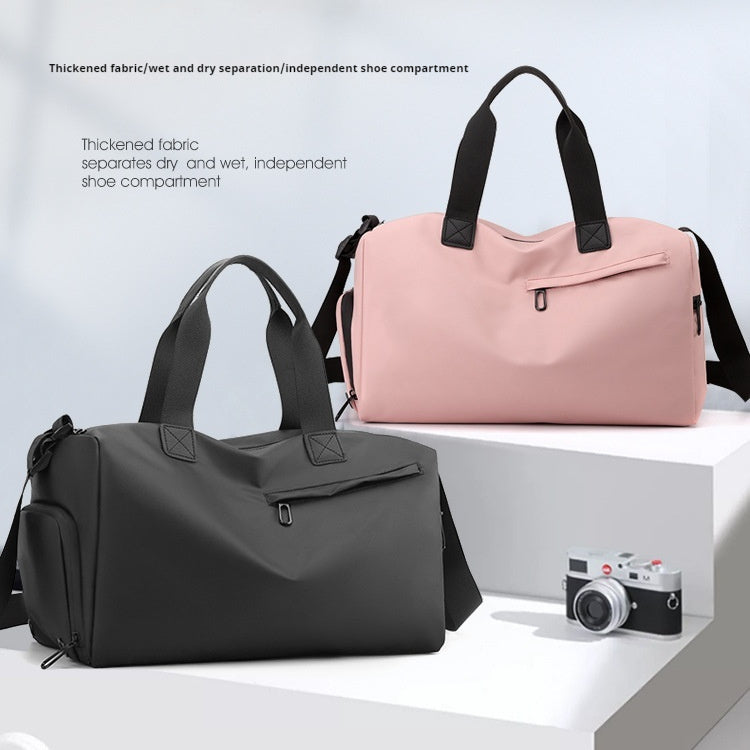 Two duffel bags, one black and one pink, on a white surface with a camera in the background.