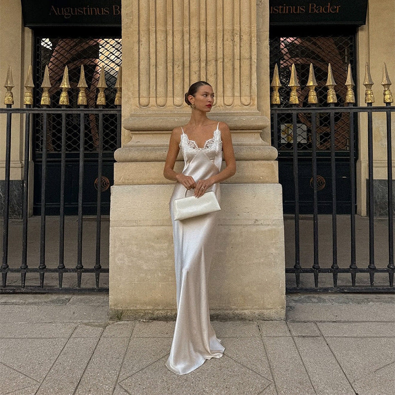 Woman in a white dress standing against a classical building facade.