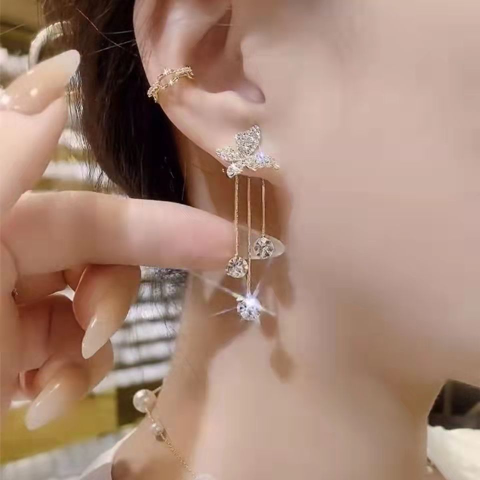 Close-up of a hand holding a star-shaped earring with a blurred background