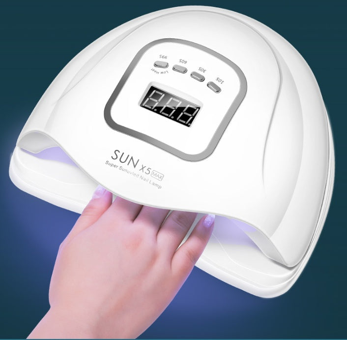 White nail dryer with digital display held by a hand against a dark background