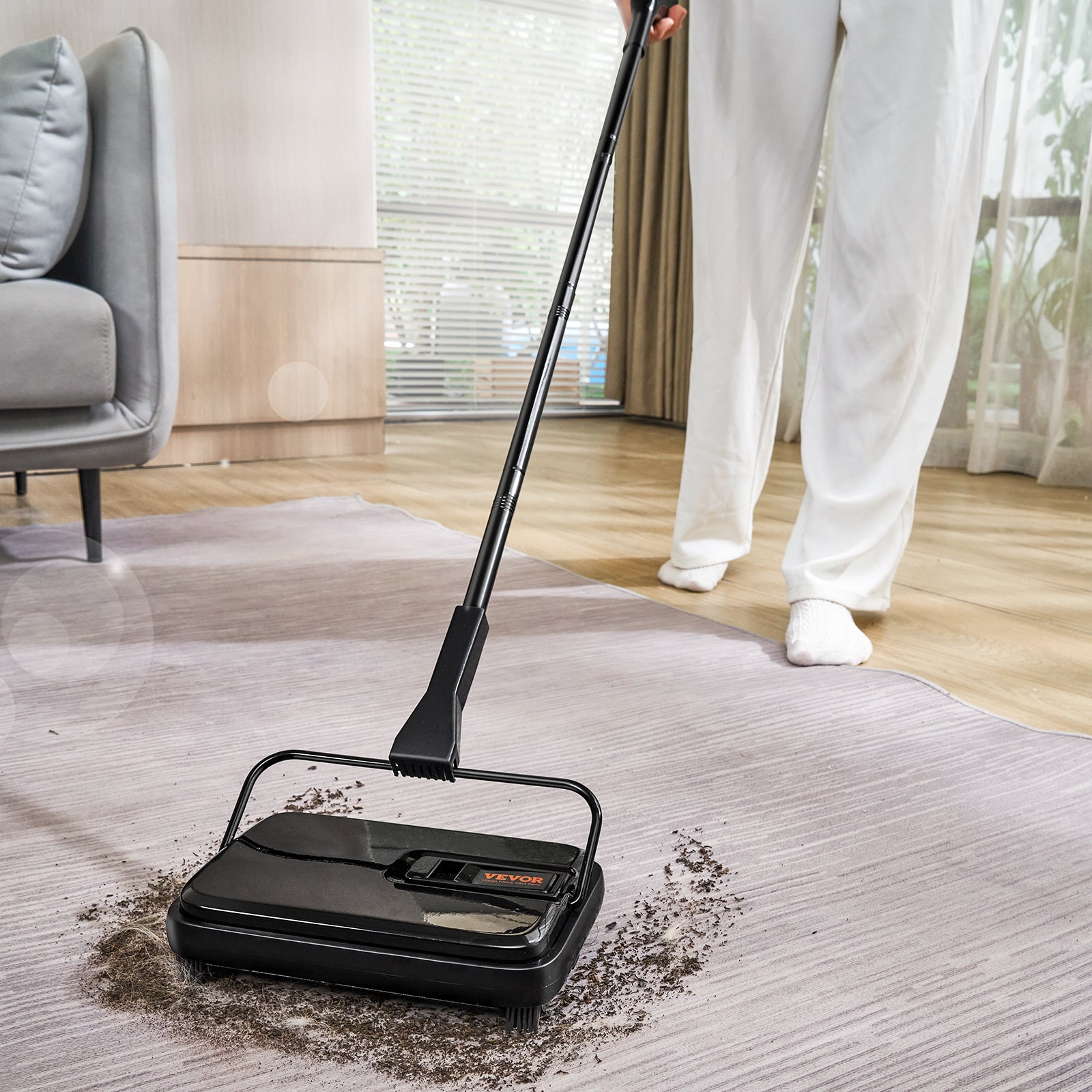 Person using a handheld vacuum cleaner on a carpet in a living room.