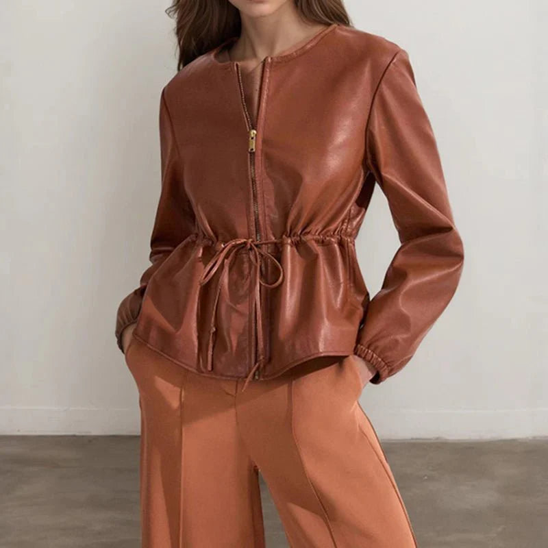 Person wearing a brown leather jacket and pants against a plain background