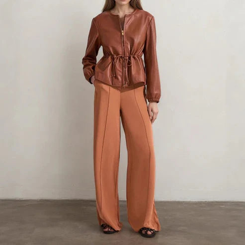 Woman wearing a brown outfit with a top and wide-leg pants against a plain background