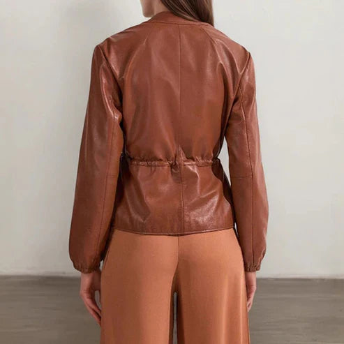 Person wearing a brown leather jacket and pants against a plain background
